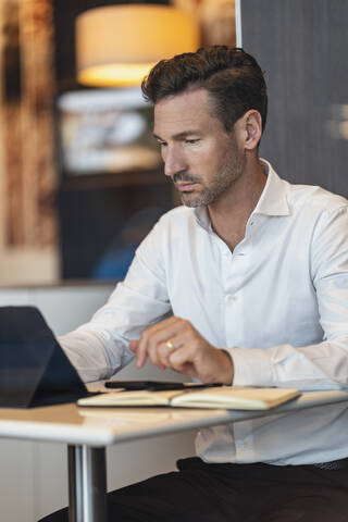 Geschäftsmann benutzt Tablet in einem Café, lizenzfreies Stockfoto