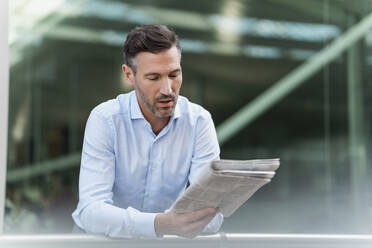 Businessman reading newspaper in the city - DIGF08428