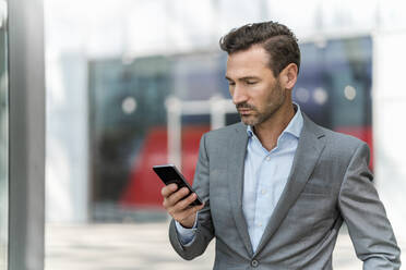 Businessman using cell phone in the city - DIGF08434