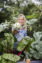 Blond smiling woman harvesting kohlrabi - HMEF00526