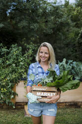 Blond woman with wooden box and organic vegetables - HMEF00531