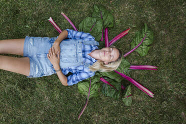 Blond woman harvesting vegetables from her raised bed in her own garden - HMEF00535