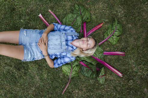 Blonde Frau bei der Ernte von Gemüse aus ihrem Hochbeet in ihrem eigenen Garten - HMEF00535