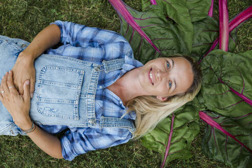 Blonde Frau bei der Ernte von Gemüse aus ihrem Hochbeet in ihrem eigenen Garten - HMEF00536