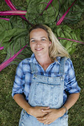 Blond woman harvesting vegetables from her raised bed in her own garden - HMEF00537