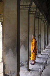 Buddhist monk in a colonnaded corridor in a temple in Angkor Wat, UNESCO World Heritage Site, Siem Reap, Cambodia, Indochina, Southeast Asia, Asia - RHPLF09224