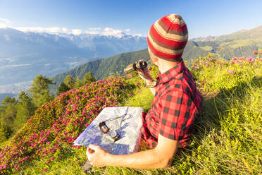 Wanderer mit Karte und Fernglas blickt vom Pizzo Berro auf die Rätischen Alpen und den Monte Disgrazia, Bitto-Tal, Lombardei, Italien, Europa - RHPLF09234