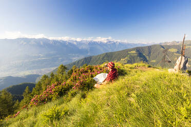 Hiker with binoculars and map looks towards Rhaetian Alps and Monte Disgrazia from Pizzo Berro, Bitto Valley, Lombardy, Italy, Europe - RHPLF09236