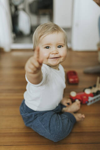 Smiling baby girl pointing finger at home stock photo