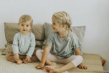 Two sisters sitting side by side at home - DWF00518