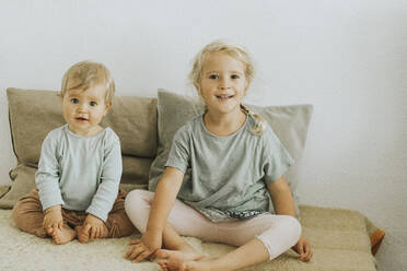 Two sisters sitting side by side at home - DWF00519