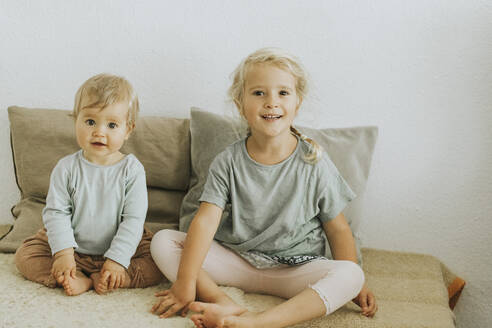 Zwei Schwestern sitzen nebeneinander zu Hause - DWF00519