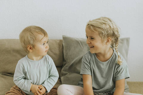 Zwei Schwestern sitzen nebeneinander zu Hause, lizenzfreies Stockfoto