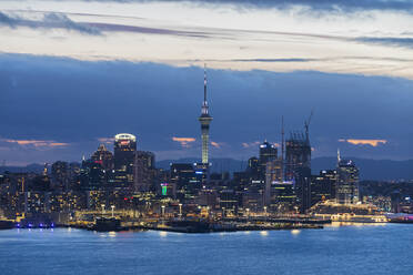 Illuminated modern buildings by sea against cloudy sky at dusk, Oceania, New Zealand - FOF10885