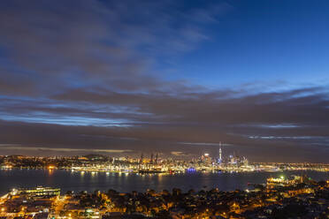 Beleuchtete moderne Gebäude am Meer gegen bewölkten Himmel in Auckland, Neuseeland - FOF10893