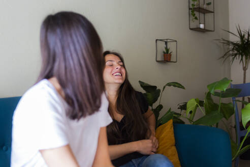 Zwei glückliche junge Frauen sitzen auf einer Couch - GIOF07045