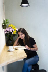 Young woman reading a book in a cafe - GIOF07050