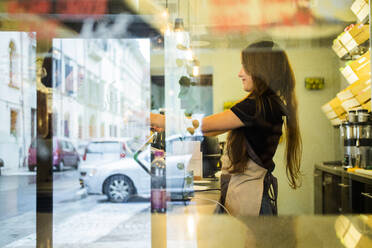 Junge Frau arbeitet an der Theke eines Cafés - GIOF07052