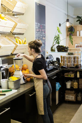 Junge Frau arbeitet in einem Café und bereitet ein frisches Getränk zu, lizenzfreies Stockfoto