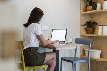 Junge Frau mit Laptop in einem Café - GIOF07073