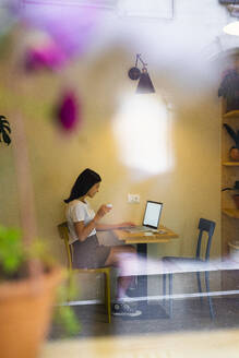 Junge Frau mit Laptop in einem Café - GIOF07077