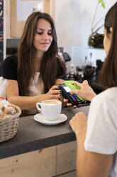 Kunde zahlt bargeldlos mit Smartphone in einem Cafe - GIOF07084