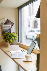 Laptop auf dem Tisch am Fenster eines Cafés - GIOF07089