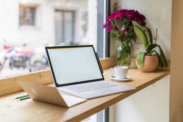 Laptop auf dem Tisch am Fenster eines Cafés - GIOF07090