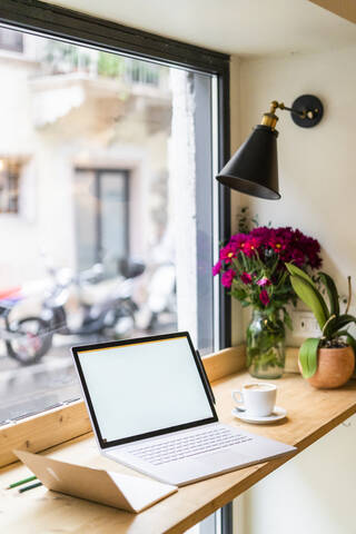 Laptop auf dem Tisch am Fenster eines Cafés, lizenzfreies Stockfoto