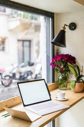 Laptop auf dem Tisch am Fenster eines Cafés - GIOF07091