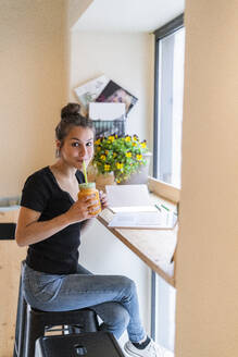 Junge Frau trinkt einen Smoothie in einem Cafe - GIOF07092