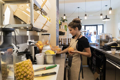 Junge Frau arbeitet in einem Café und bereitet ein frisches Getränk zu, lizenzfreies Stockfoto