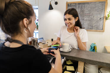 Kunde zahlt bargeldlos mit Smartphone in einem Cafe - GIOF07103