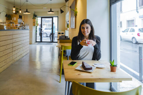 Porträt einer lächelnden jungen Frau, die in einem Café sitzt - GIOF07107