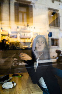 Junge Frau in einem Café hinter der Fensterscheibe - GIOF07110