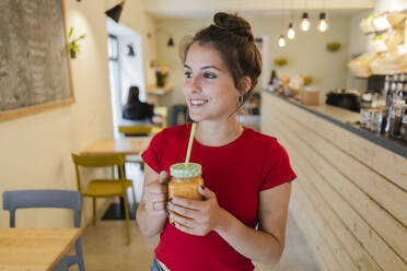 Porträt einer jungen Frau mit einem Smoothie in einem Café - GIOF07123