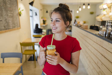 Portrait of a young woman with a smoothie in a cafe - GIOF07123