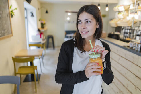 Porträt einer jungen Frau mit einem Smoothie in einem Café - GIOF07126