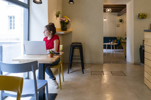Junge Frau mit Laptop in einem Café - GIOF07127