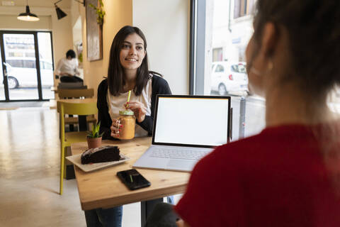Two young women with laptop in a cafe stock photo