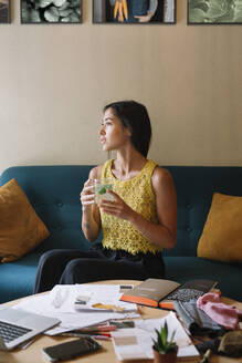 Modedesigner, der auf der Couch sitzt, eine Pause macht und Tee trinkt - ALBF01121