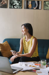 Smiling fashion designer sitting on couch having a break - ALBF01124