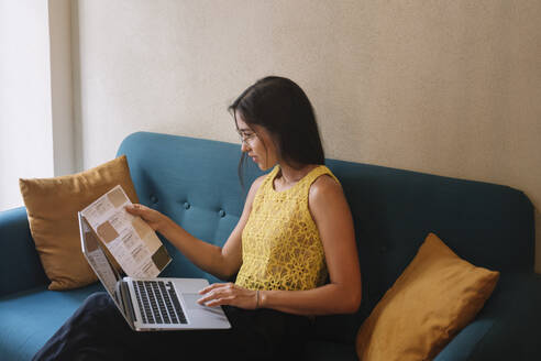 Fashion designer sitting on couch checking color samples - ALBF01134