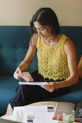 Fashion designer sitting on couch checking color samples - ALBF01136
