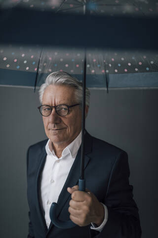 Porträt eines älteren Geschäftsmannes mit Regenschirm, lizenzfreies Stockfoto