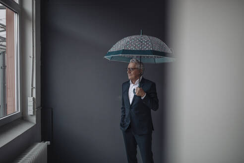 Senior businessman holding umbrella - GUSF02547