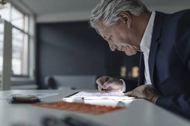 Älterer Geschäftsmann zeichnet auf leuchtendem Tablet - GUSF02556