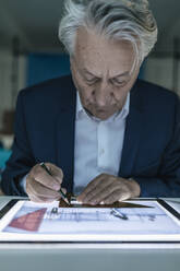 Älterer Geschäftsmann zeichnet auf leuchtendem Tablet - GUSF02559