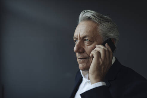 Porträt eines älteren Geschäftsmannes, der mit einem Mobiltelefon spricht - GUSF02580