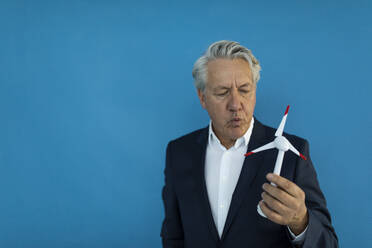 Senior businessman holding wind turbine model - GUSF02592